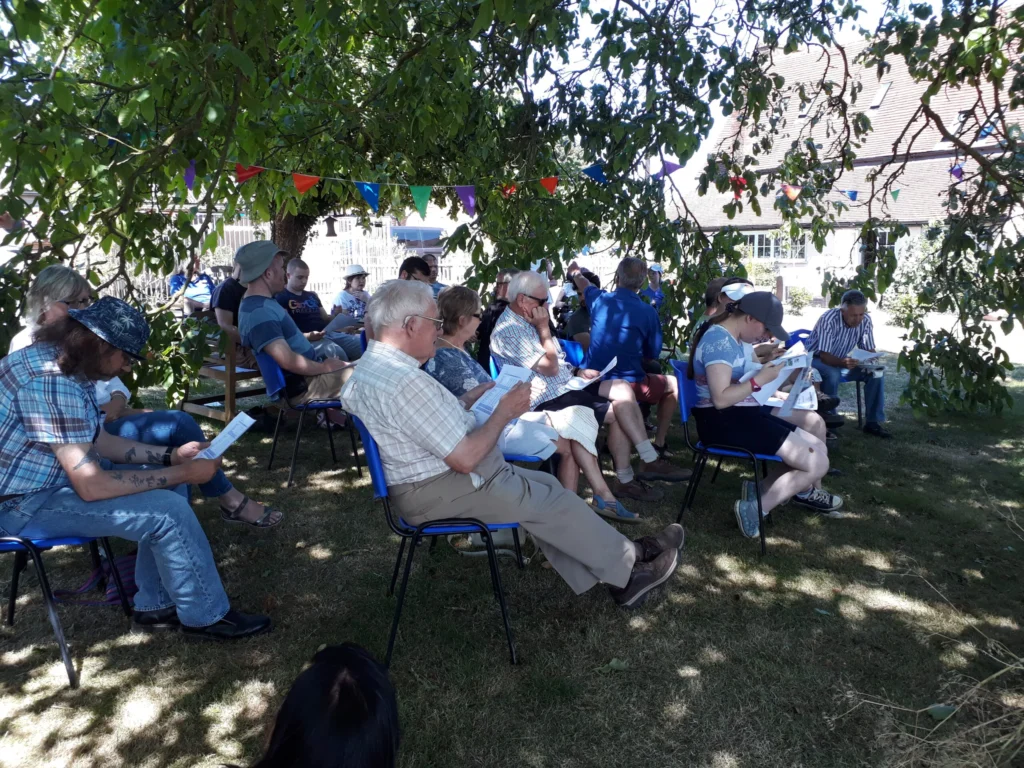 people sitting on chairs at the farm reading through a document