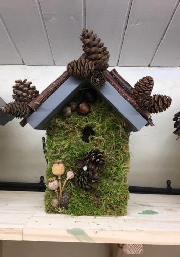 Birdbox decorated with pinecones, sticks and moss